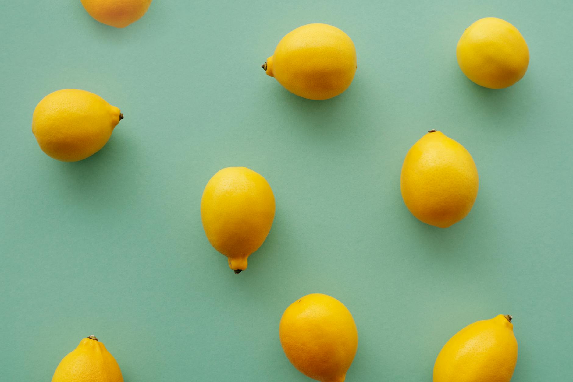 Bright yellow lemons on a soft pastel green background, symbolizing freshness and new beginnings