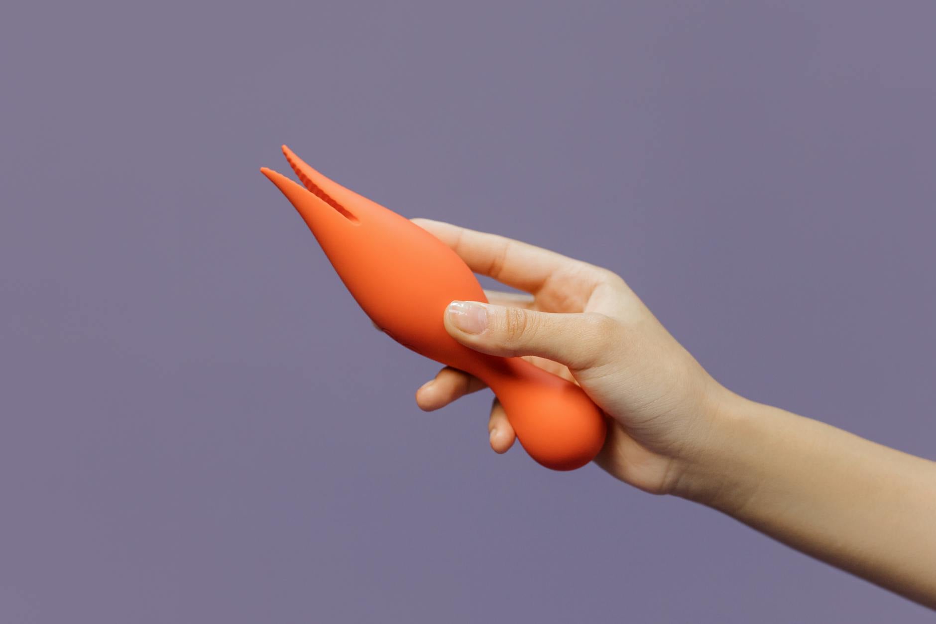 A woman holding colorful vibrators against a purple background, representing choice and body autonomy