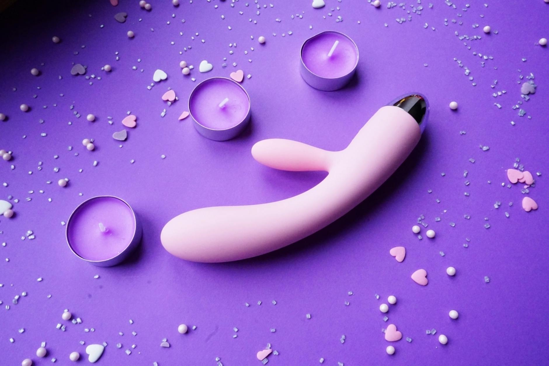 Pink lemon clitoral vibrator on purple background with romantic ambiance