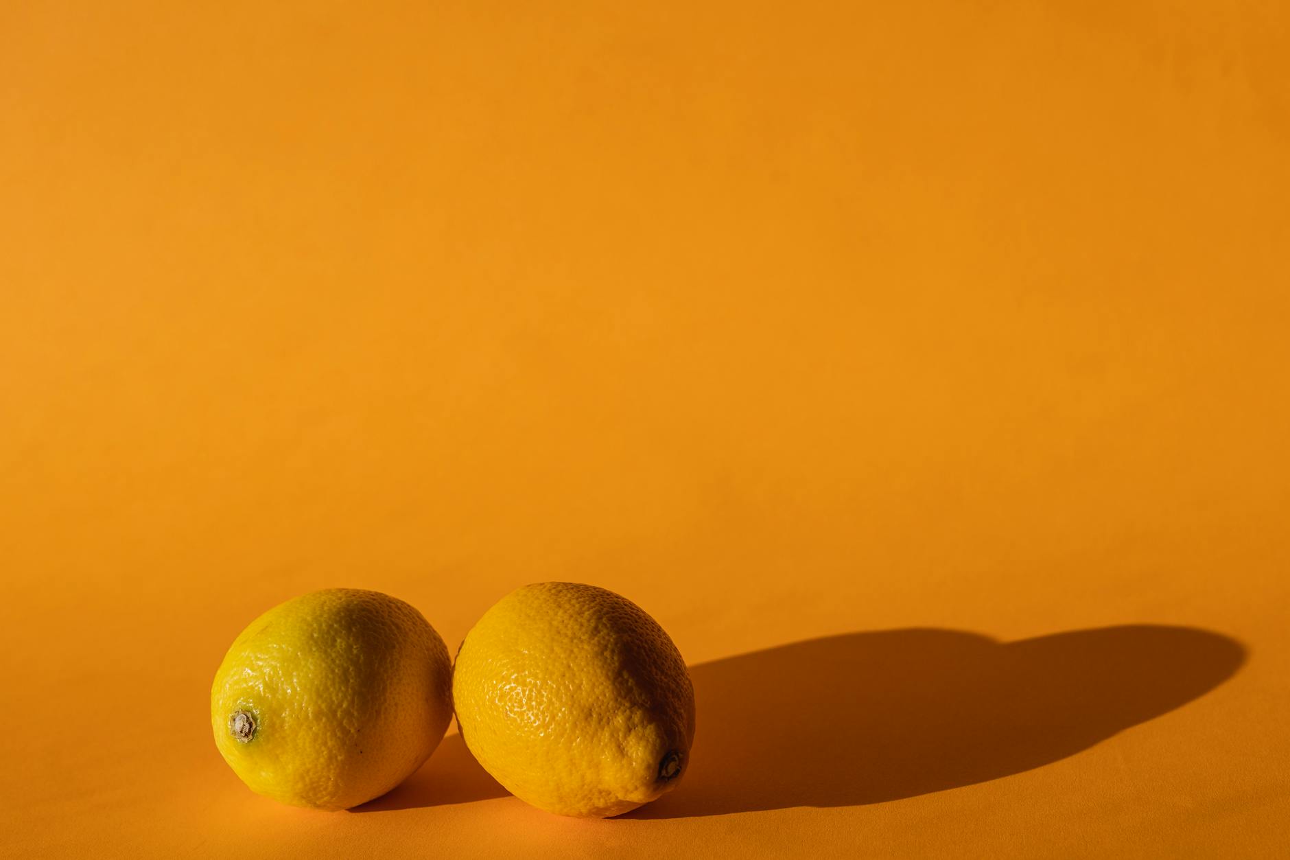 Ripe vivid lemons on a yellow background, symbolizing the lemon vibrator and aging wellness